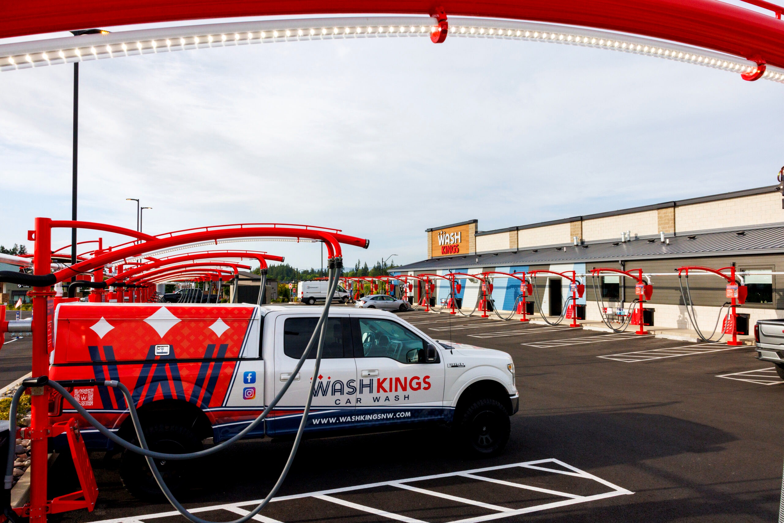 Wash Kings branded fleet truck at the vacuum lot with the Wash Kings building sign and red vacuum arches